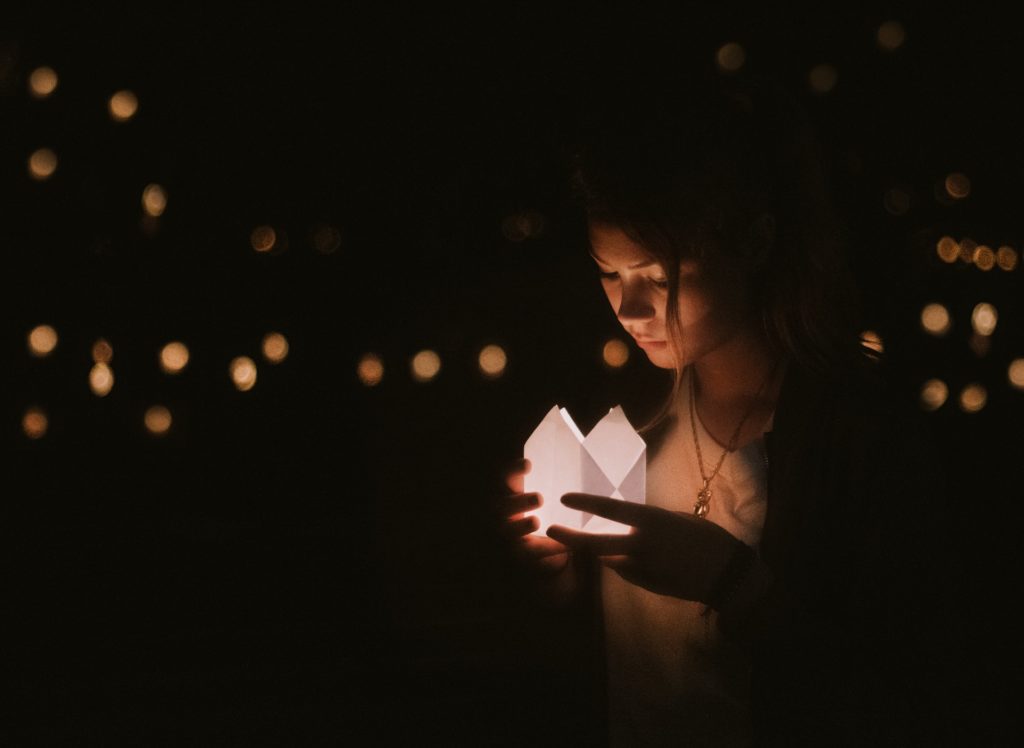 young woman holding candlelit white lantern
