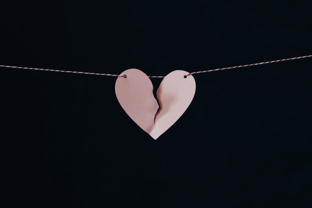 black background with light pink heart torn down the middle