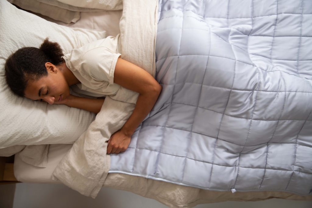 woman sleeping on her side with white down comforter